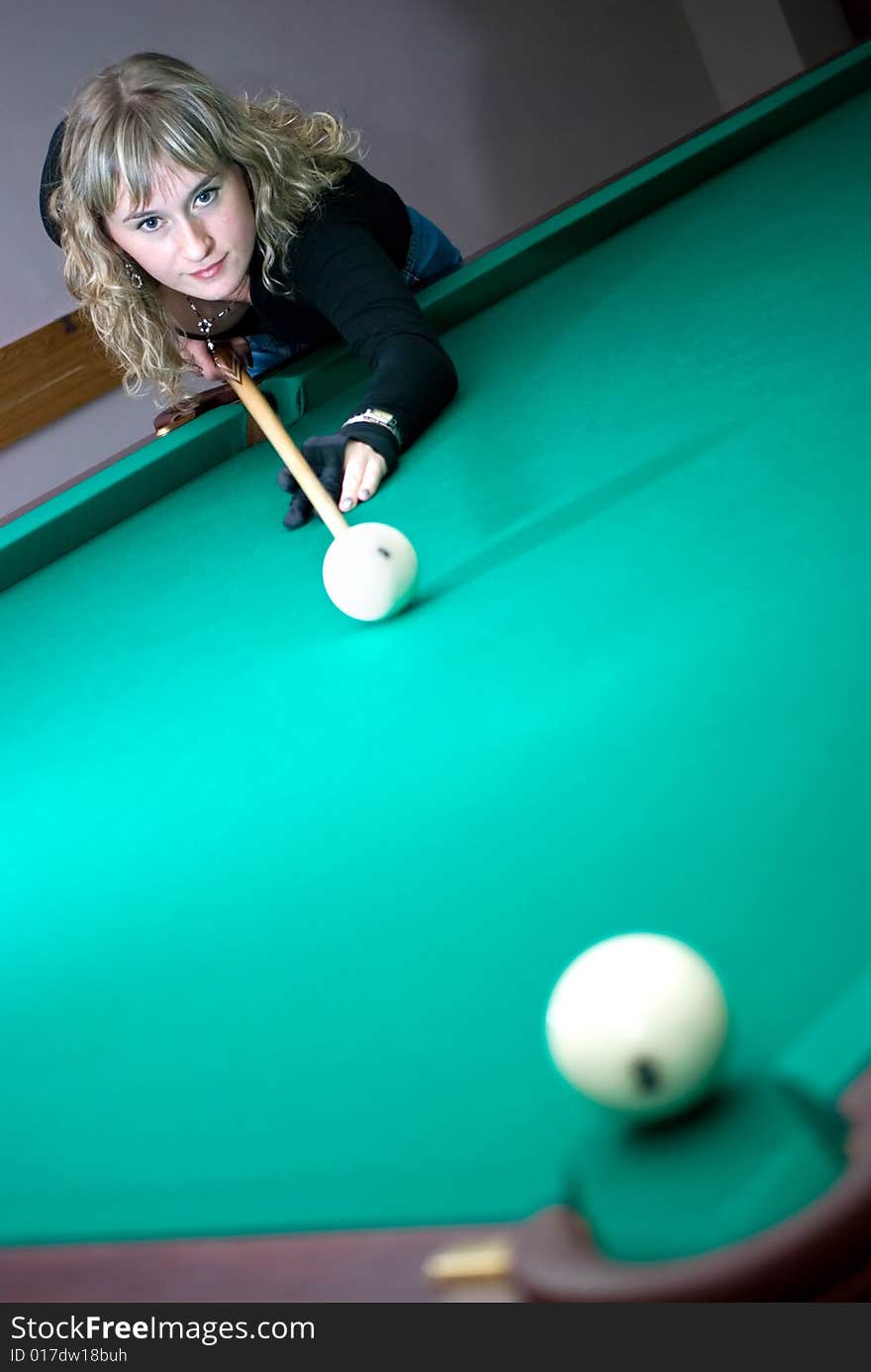 The girl beat the ball into a billiard pocket. The girl beat the ball into a billiard pocket