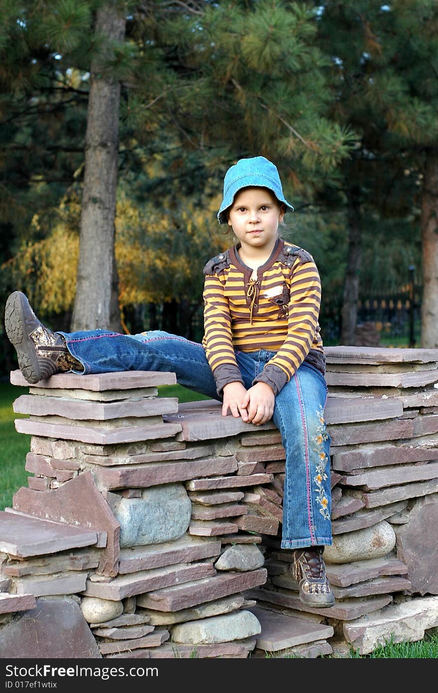 Little girl sitting on the stone in the park