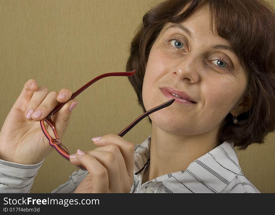 A woman keeps glasses in the hands of and looking on to the camera. A woman keeps glasses in the hands of and looking on to the camera