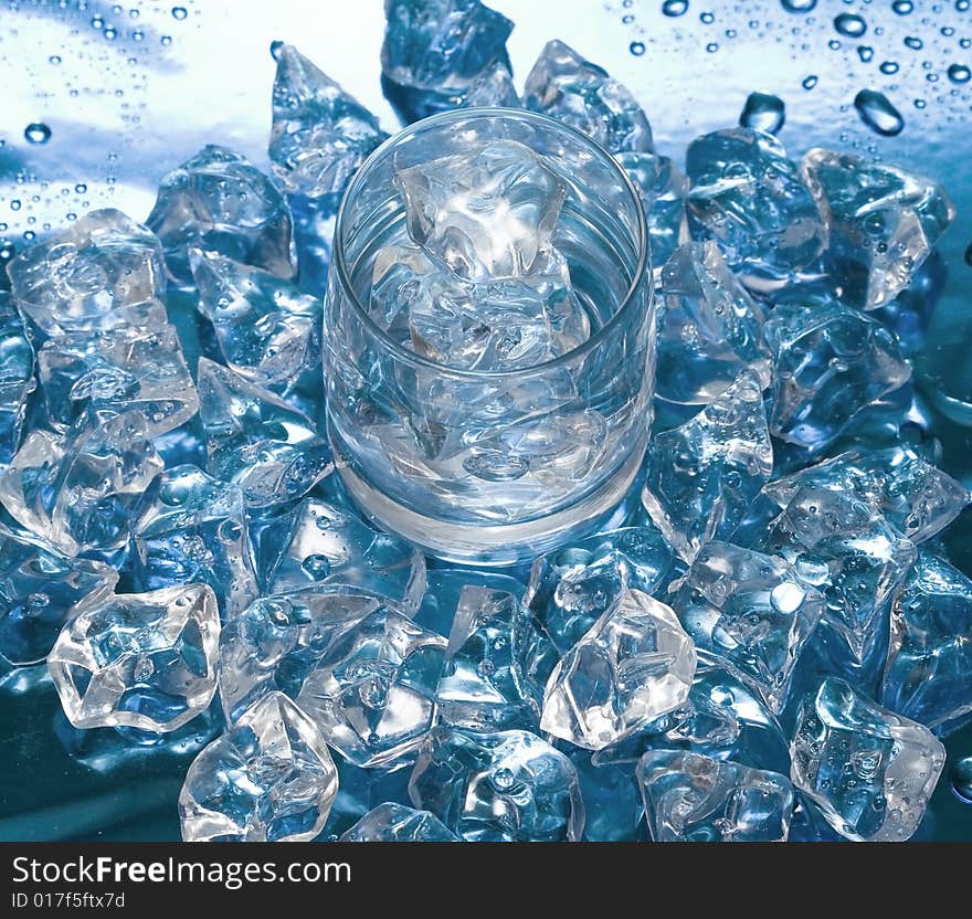 Glass with water and ice over blue