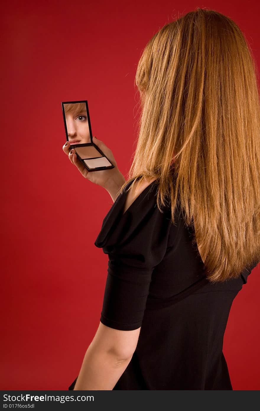 Beautiful girl looking in mirror, face in reflection, focus on hair