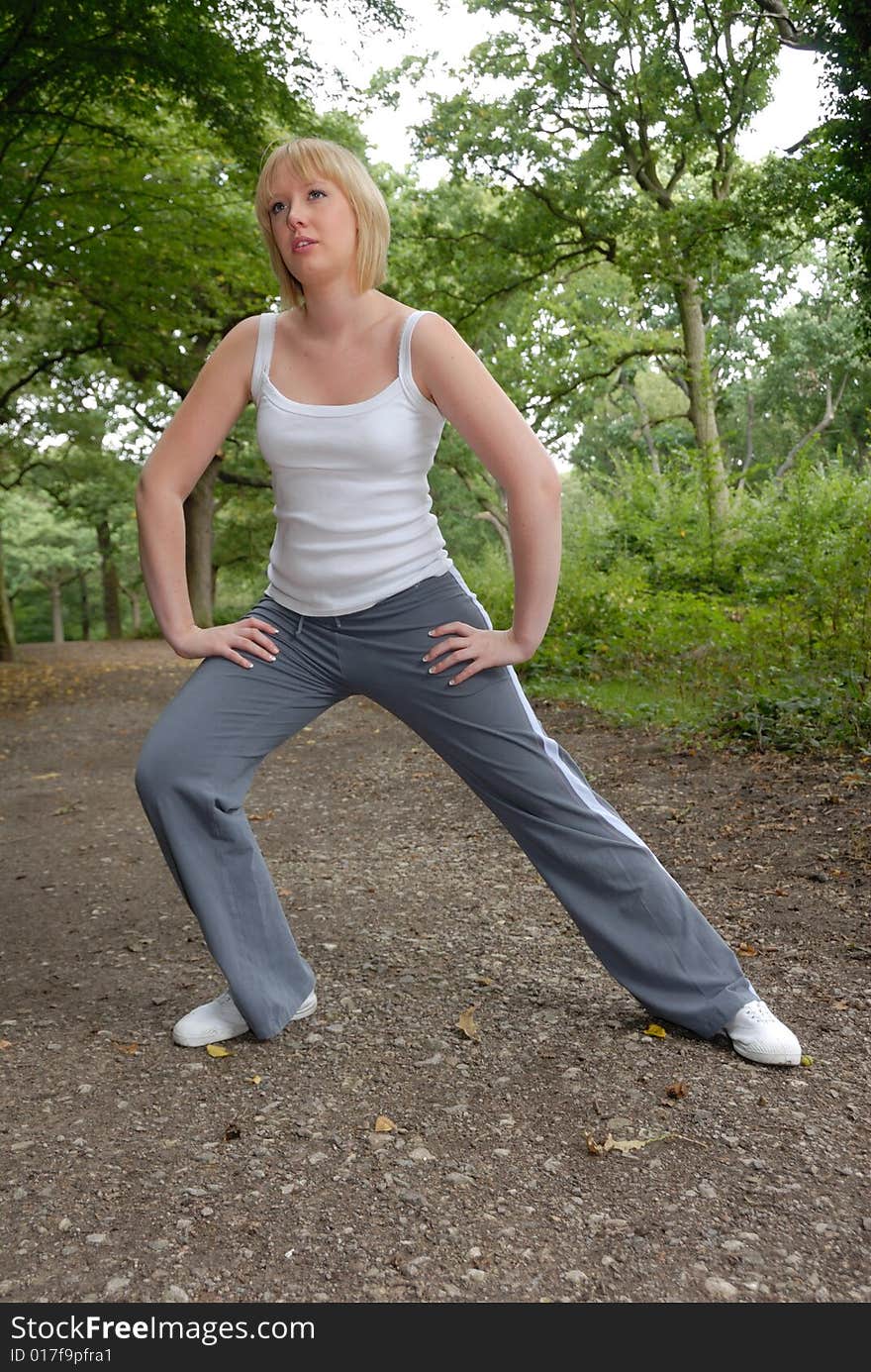 Cute blond girl outdoors doing stretching exercises. Cute blond girl outdoors doing stretching exercises