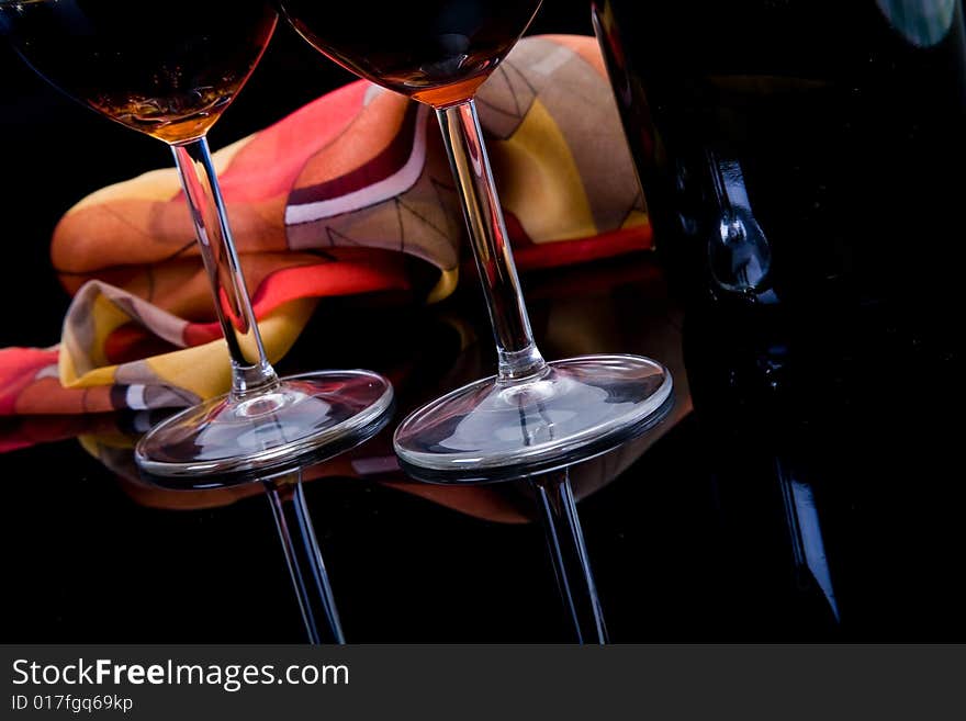 Glass, bottle and shawl on dark background