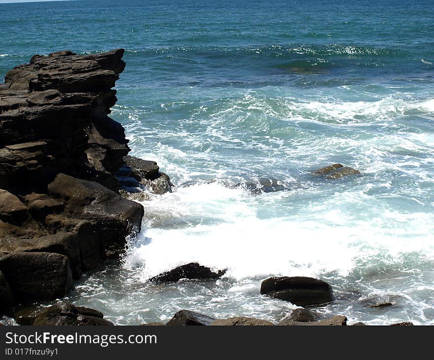 Water splashing up to rocks at the beach. Water splashing up to rocks at the beach.