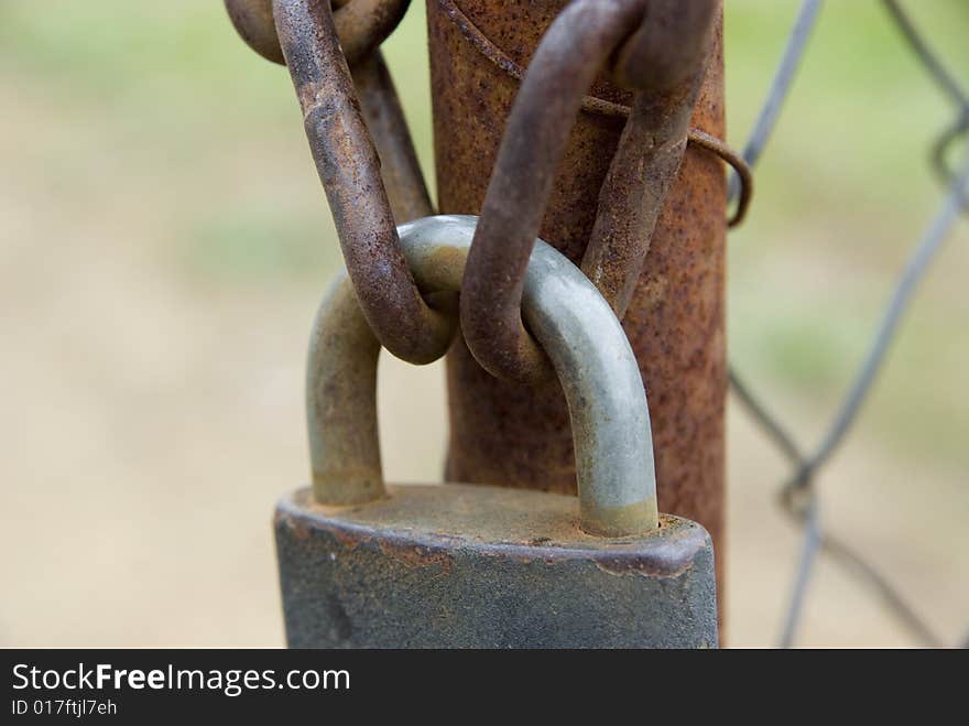 Padlock and chains on the rusty gate