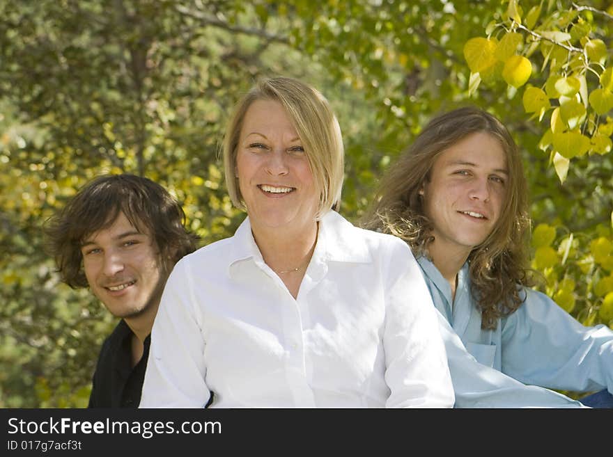 Photo of single mom with her two teenage boys. Warm tones with fall background. Relatively shallow DOF with focus on the mother. Photo of single mom with her two teenage boys. Warm tones with fall background. Relatively shallow DOF with focus on the mother.