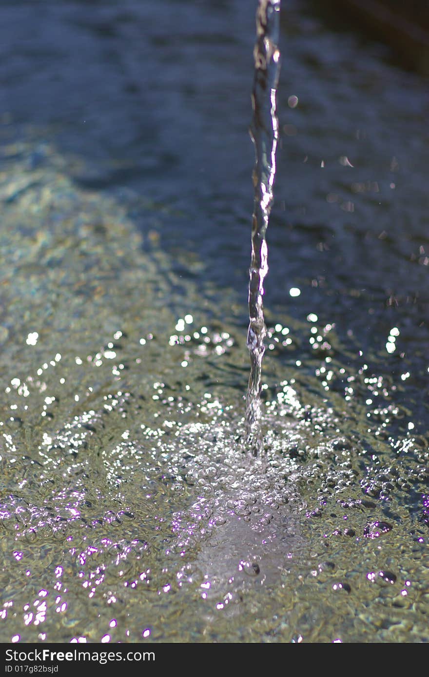 Dropping potable stream of water in sunlight, vertical. Dropping potable stream of water in sunlight, vertical