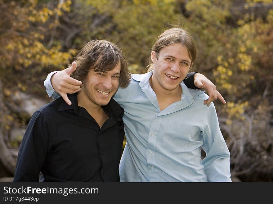 Brothers smiling and the camera and clowning around in a fall outdoor setting.