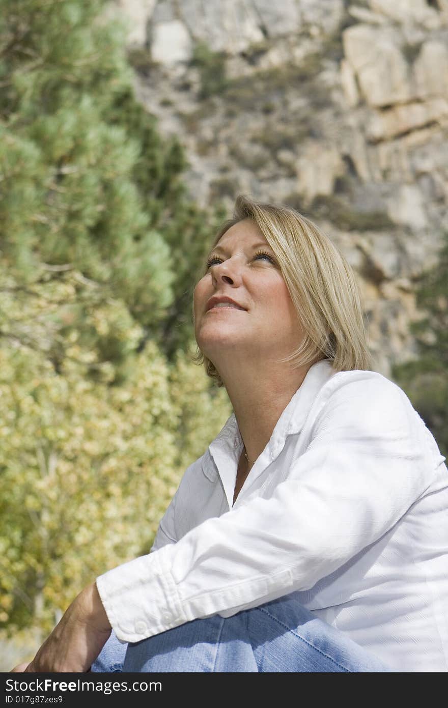 Healthy mature woman in an outdoor setting looking up at the sky. Healthy mature woman in an outdoor setting looking up at the sky.