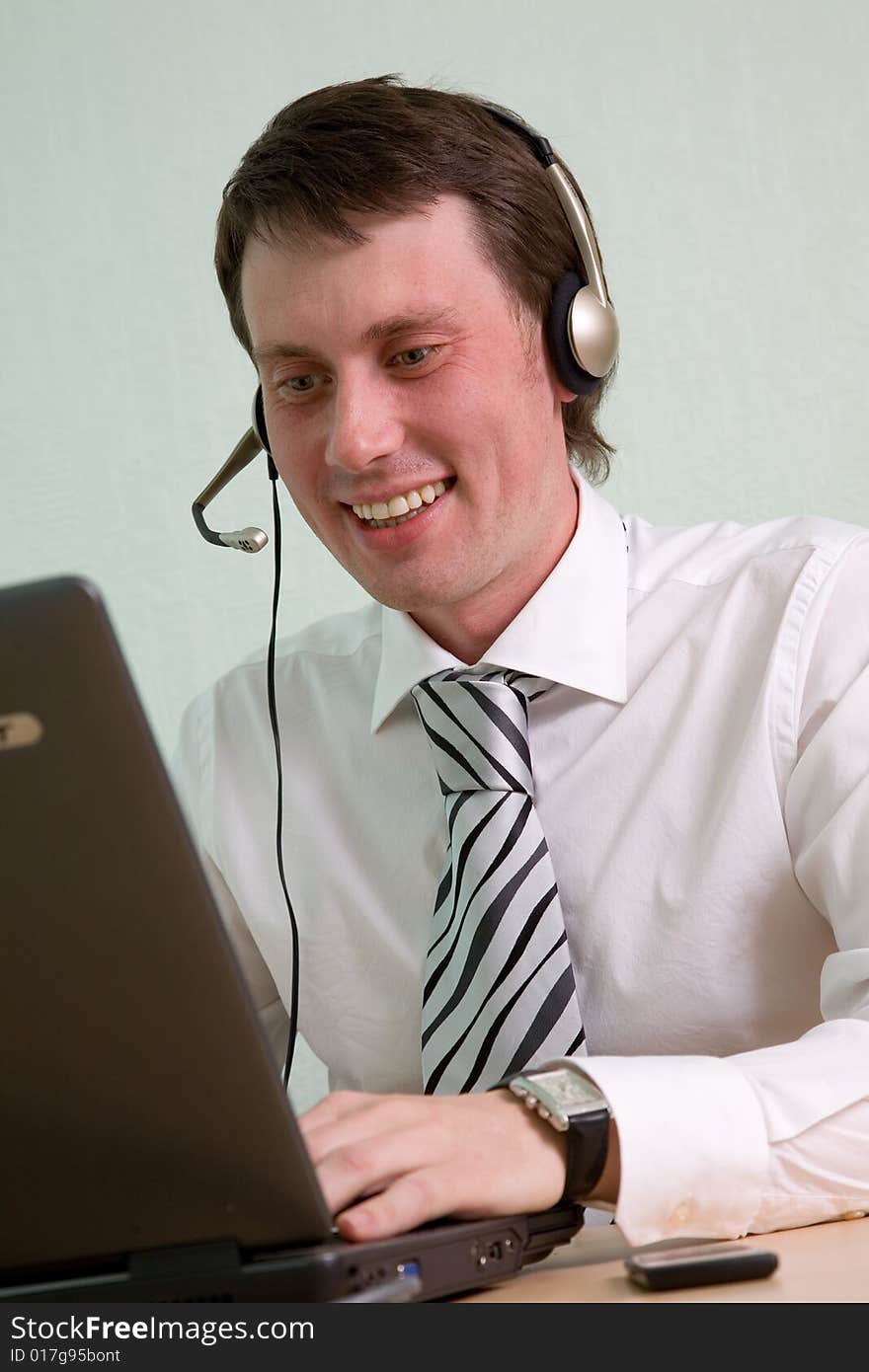 The young businessman speaks by phone and works on a computer