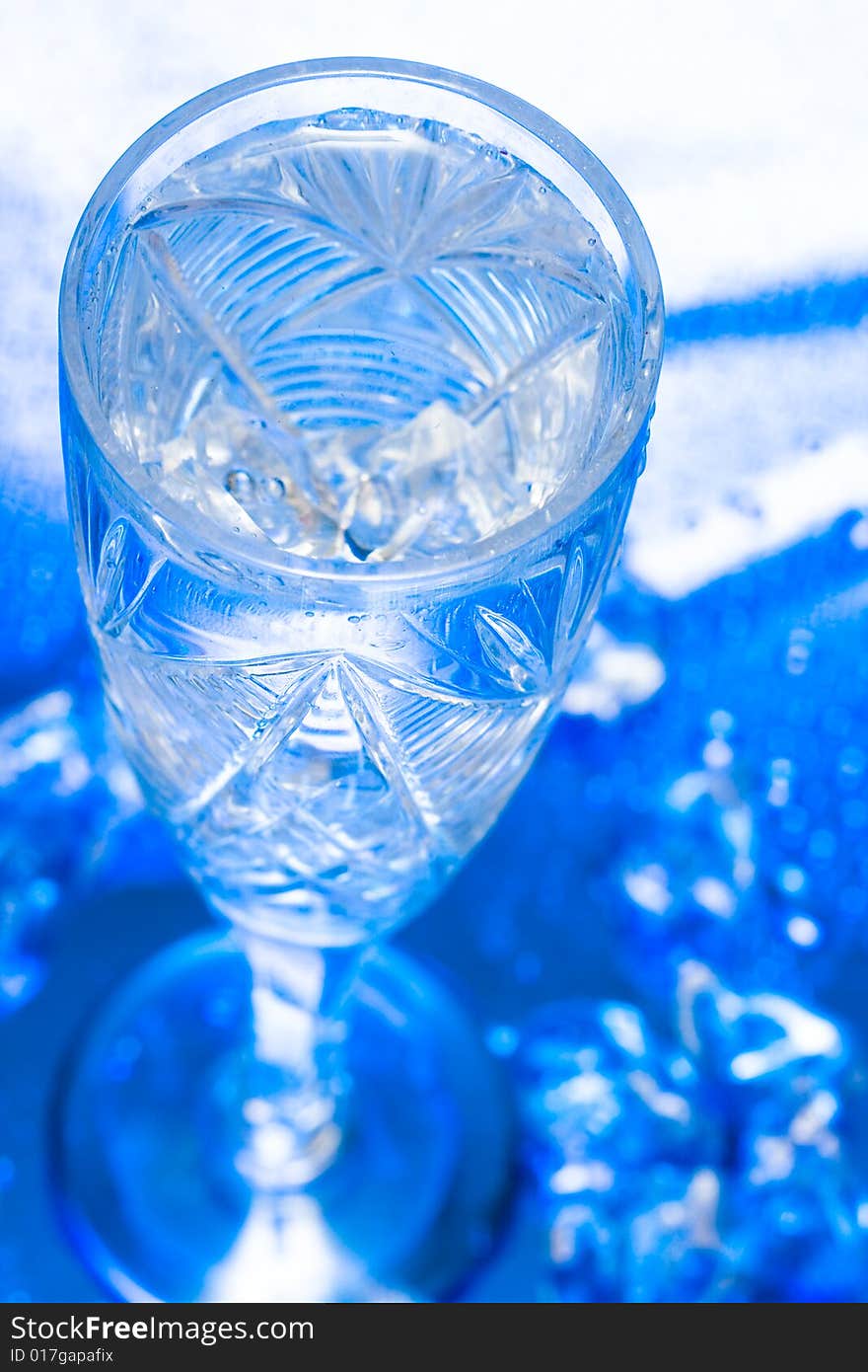 Glass with water and ice over blue