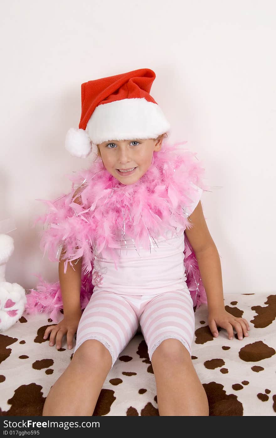 Smiling cute girl with christmas hat sitting on the bed. Smiling cute girl with christmas hat sitting on the bed