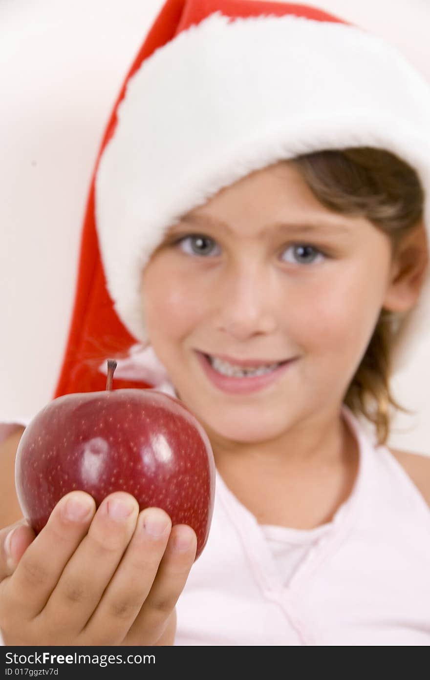 Girl wearing christmas hat and holding an apple in the palm of her hands