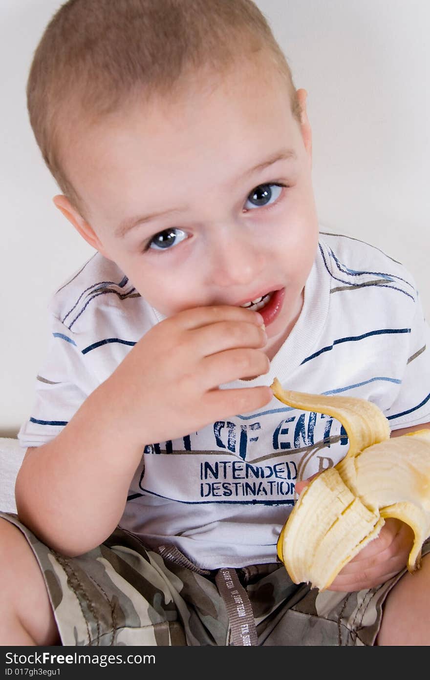 Close up of cute boy holding peeled banana