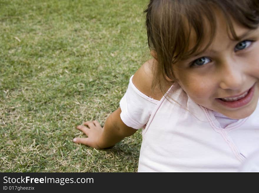 Close view of smiling little girl sitting on  grass. Close view of smiling little girl sitting on  grass