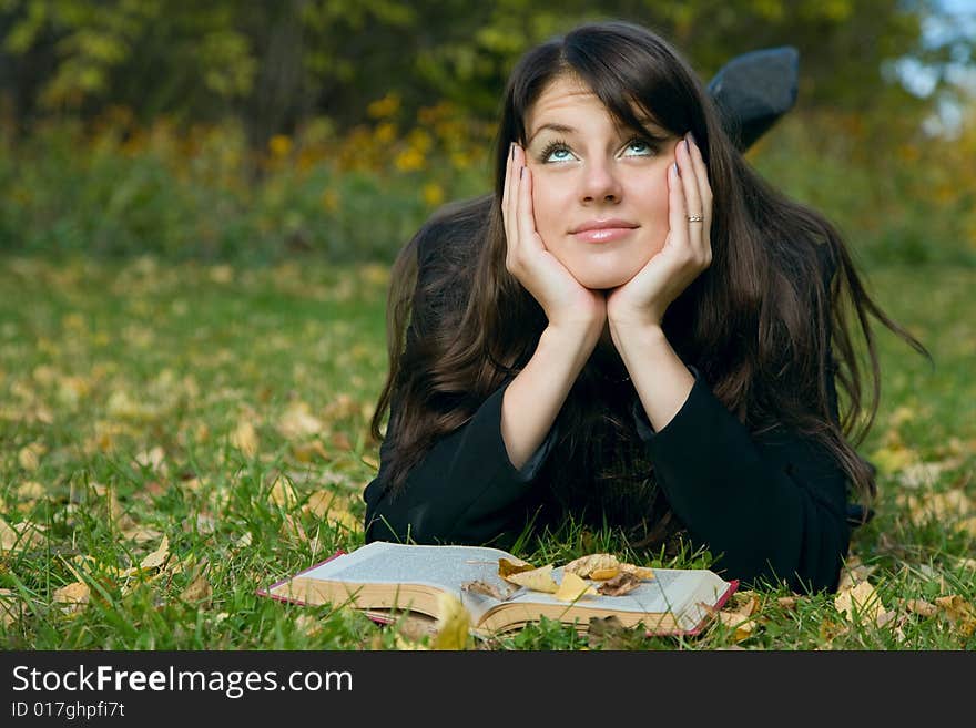 Young girl reading a book on the meadow