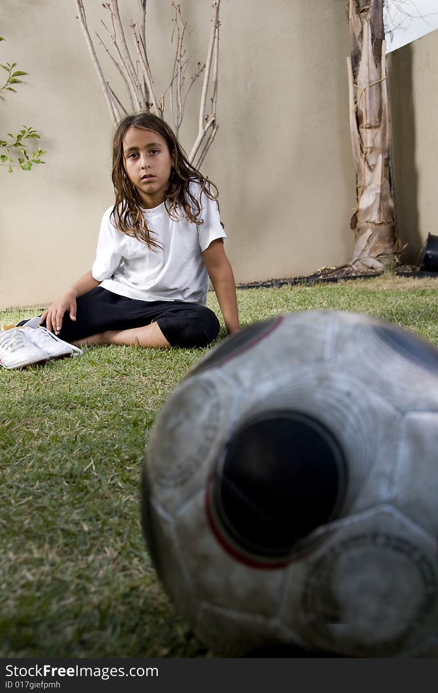 Tired boy sitting near soccer ball