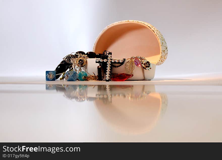 An open jewelry box with the jewels spilling out and the reflection of the box in front.