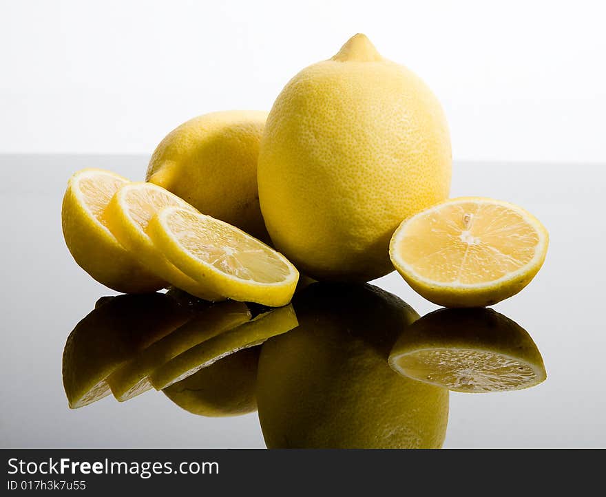 Sliced and whole yellow lemons on mirrored background. Sliced and whole yellow lemons on mirrored background