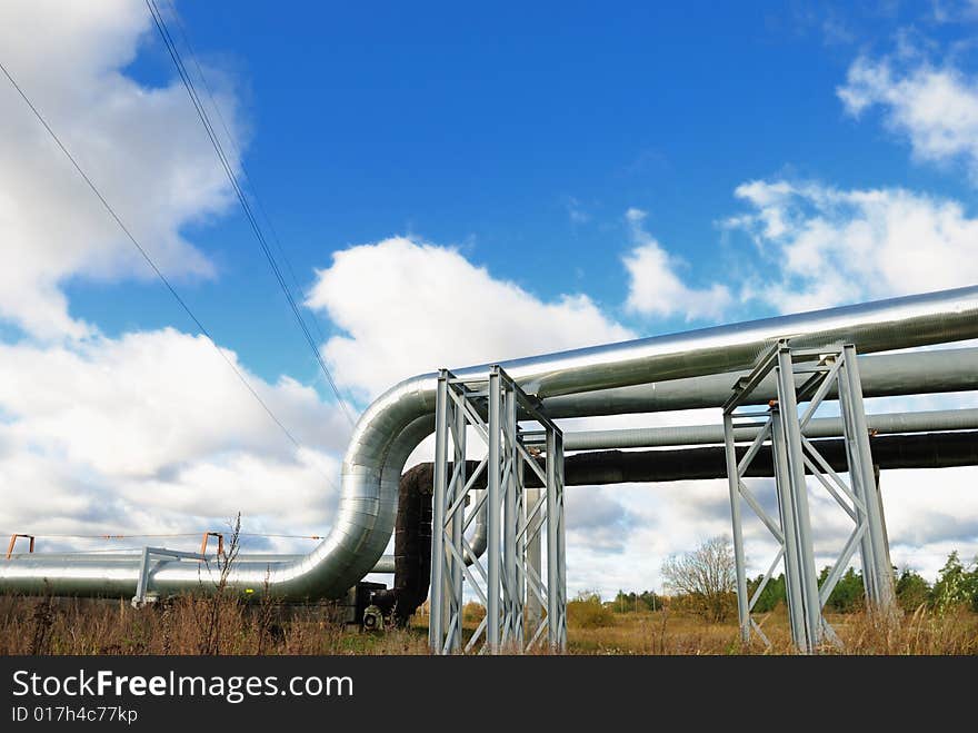 Industrial pipelines on pipe-bridge against blue sky.