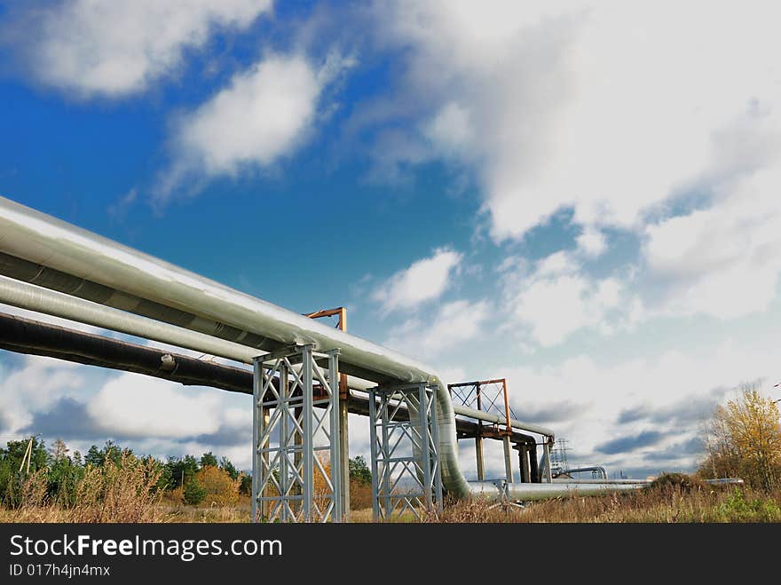 Industrial pipelines on pipe-bridge against blue sky.