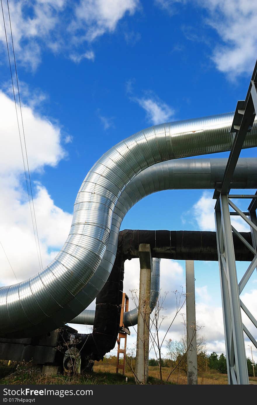 Industrial pipelines on pipe-bridge against blue sky.