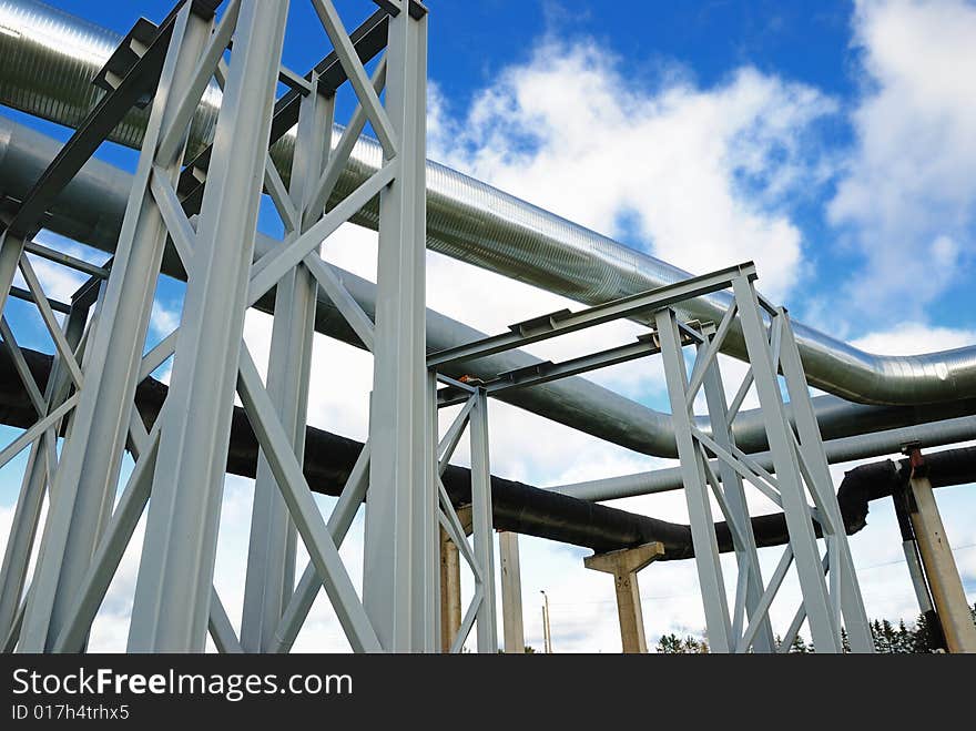 Industrial pipelines on pipe-bridge against blue sky.