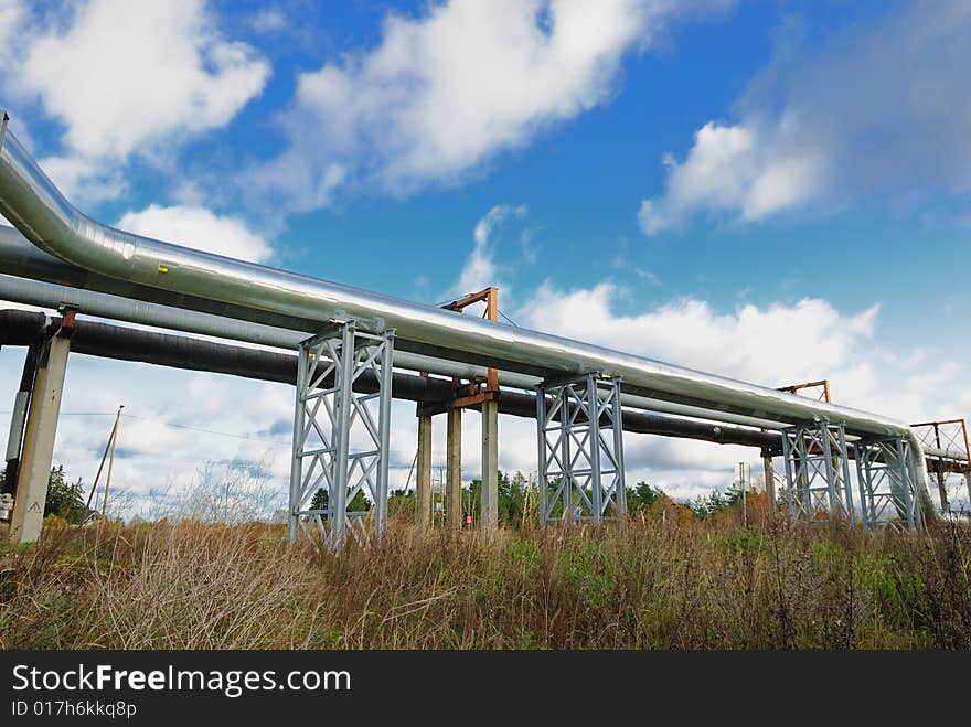 Industrial pipelines on pipe-bridge against blue sky.