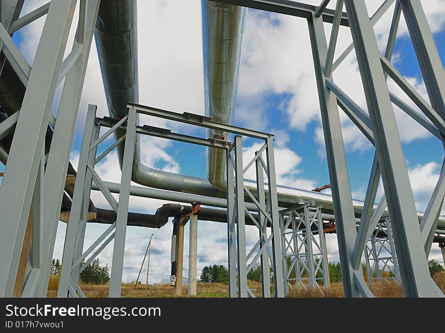 Industrial pipelines on pipe-bridge against blue sky.