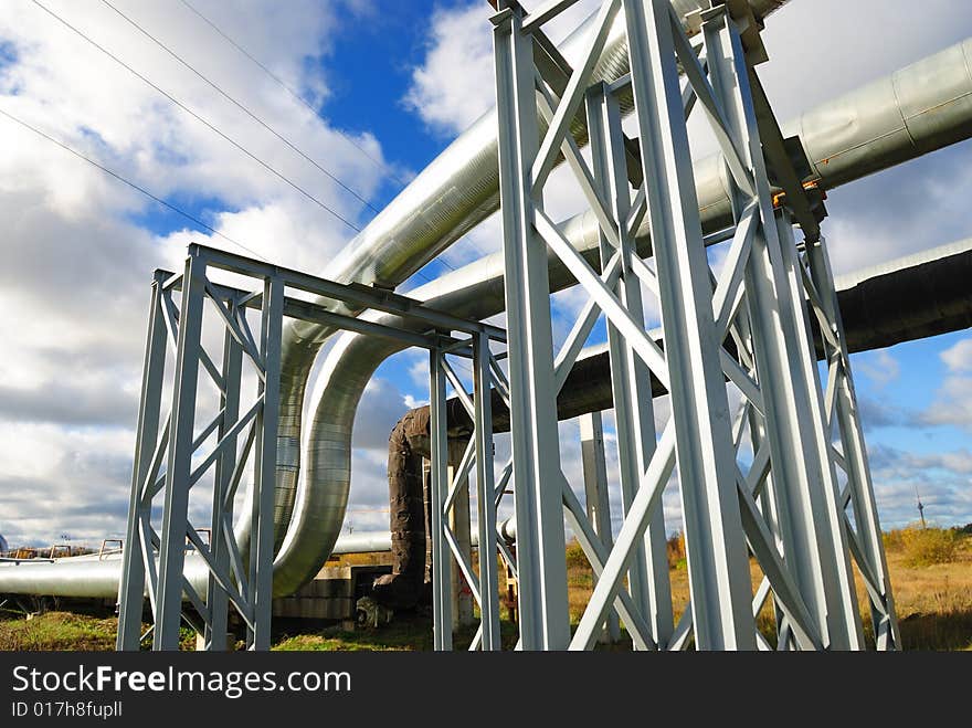 Industrial pipelines on pipe-bridge against blue sky.