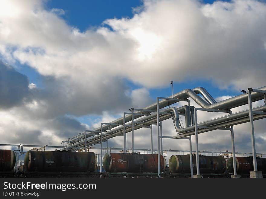 Industrial pipelines on pipe-bridge against blue sky.