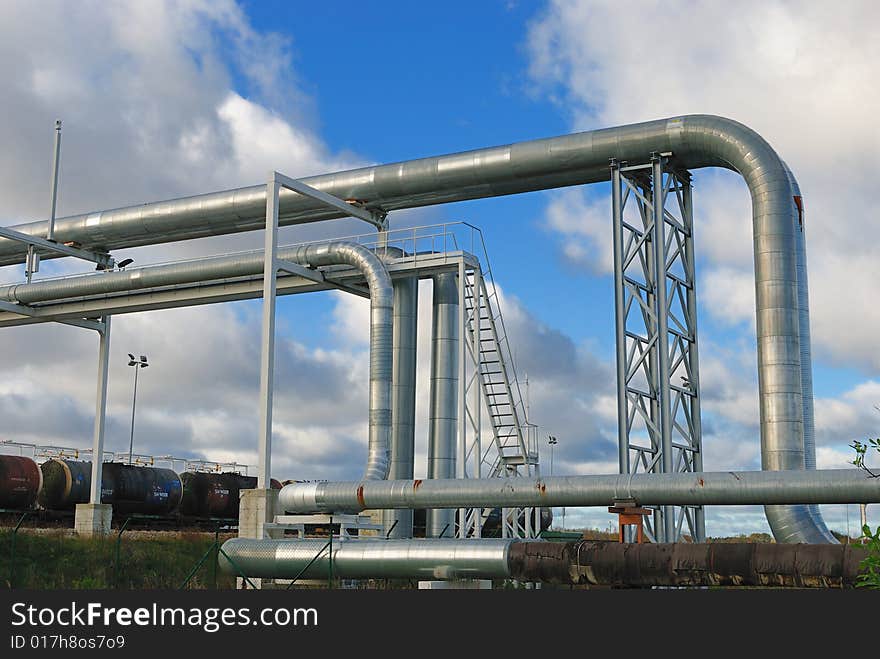 Industrial pipelines on pipe-bridge against blue sky.