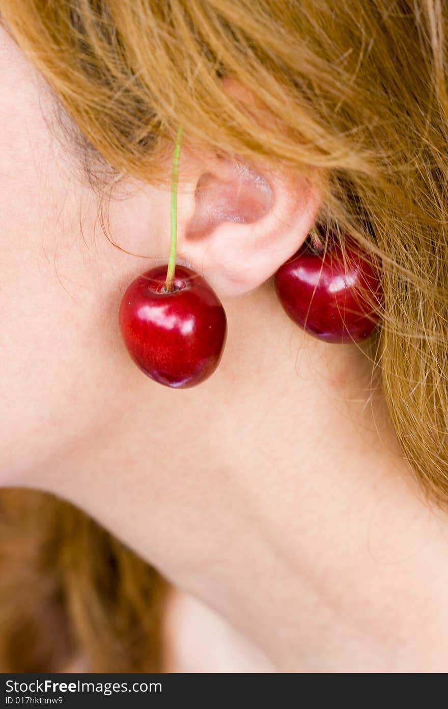 Woman ear with cherry earrings