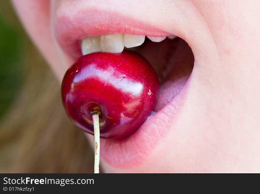 Closeup of a woman biting a red cherry