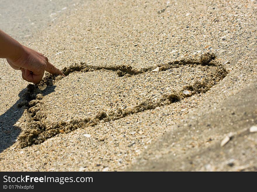 Drawing a heart in wet sand