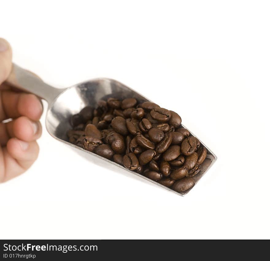 Coffee beans falling from silver shovel set against white background