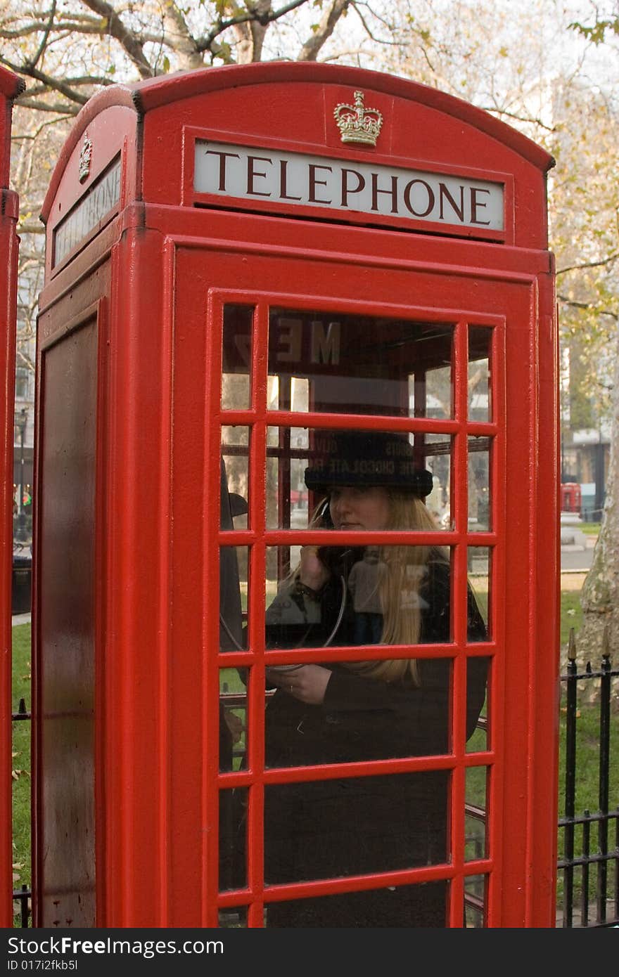 Blonde woman talking on the phone in a London Call Box. Blonde woman talking on the phone in a London Call Box