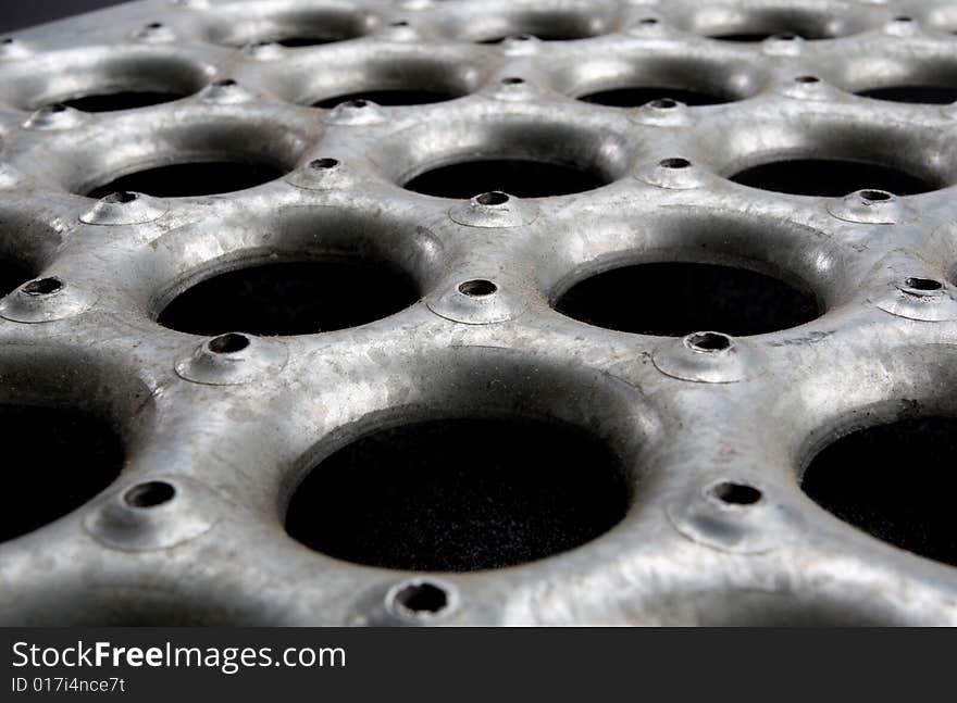 Grungy metal floor material extreme close-up at an angle. Grungy metal floor material extreme close-up at an angle.