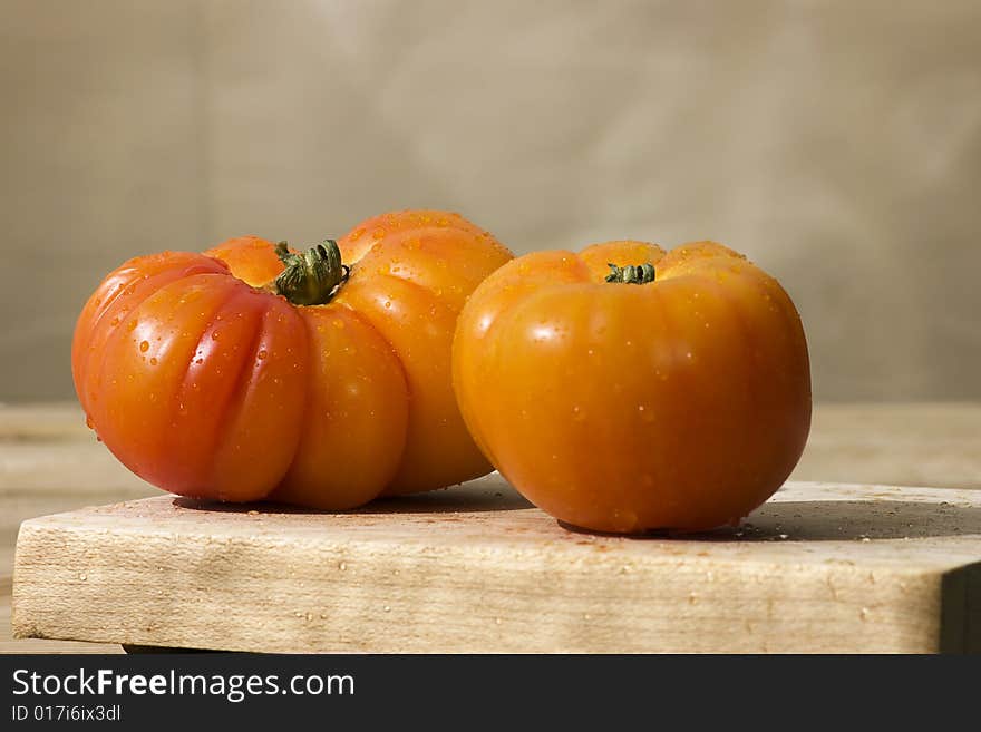 A pair of heirloom tomatoes on a tabletop, natural lighting and waterdrops. A pair of heirloom tomatoes on a tabletop, natural lighting and waterdrops.