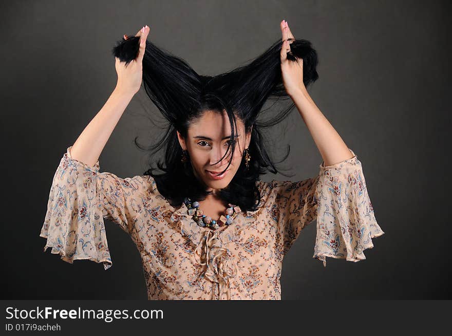 Portrait of young stylish brunette woman holding her hair