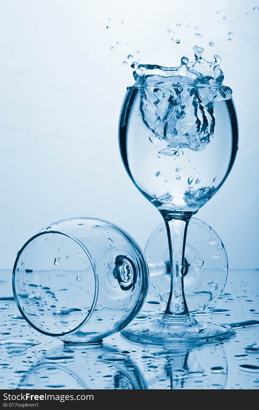 Pure water splashing into glass toned blue