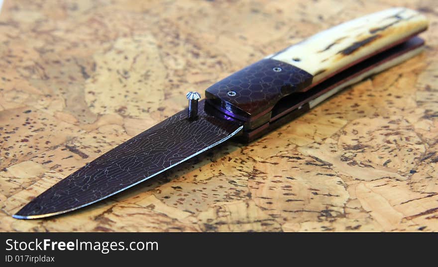 Stainless steel pocket knife isolated on the wood background