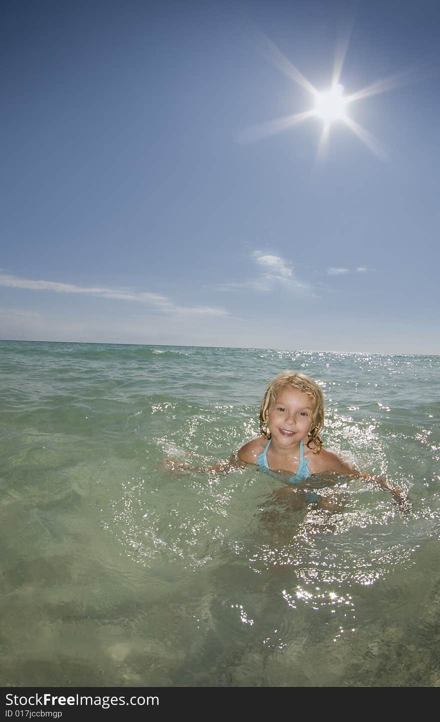 A young girl plays in the ocean on a calm bright sunny day. A young girl plays in the ocean on a calm bright sunny day