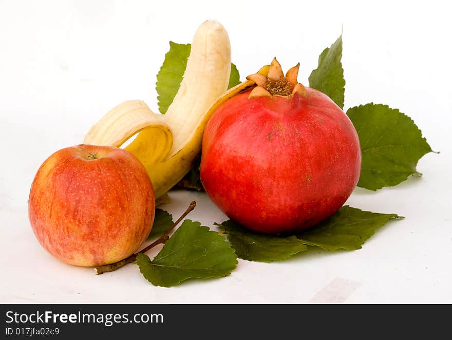 Pomegranate, apple, and banana on leaves. Pomegranate, apple, and banana on leaves