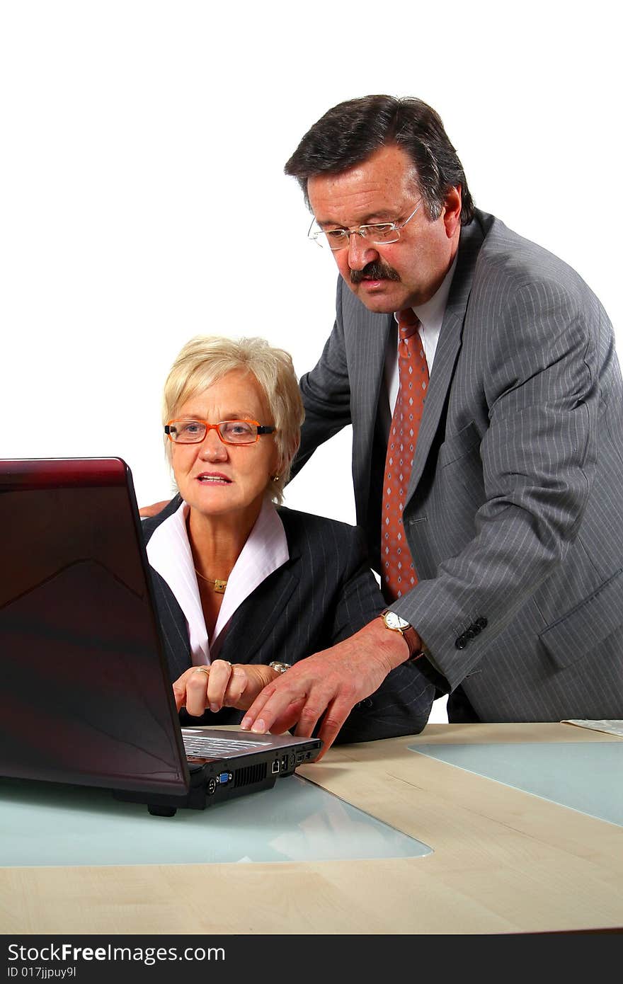 A business woman and a man in front of a laptop on a desk. The man explains something to the woman. Isolated over white. A business woman and a man in front of a laptop on a desk. The man explains something to the woman. Isolated over white.