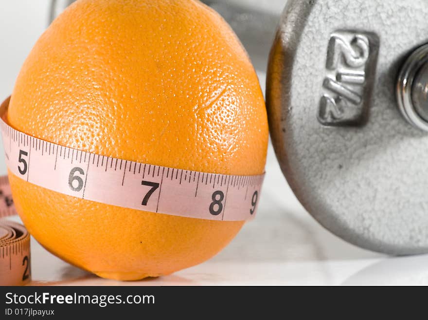 Orange with a measuring tape aound it by weights. Orange with a measuring tape aound it by weights.