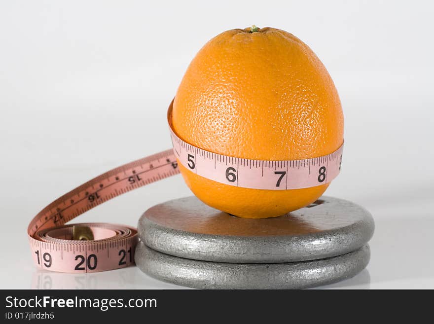 Orange with a measuring tape aound it by weights. Orange with a measuring tape aound it by weights.