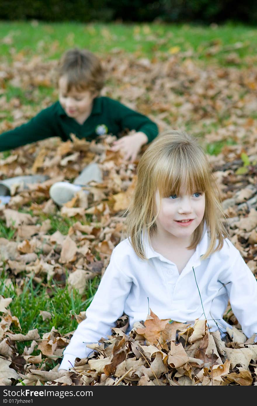 A set of boy girl twins playing in the autumn leaves