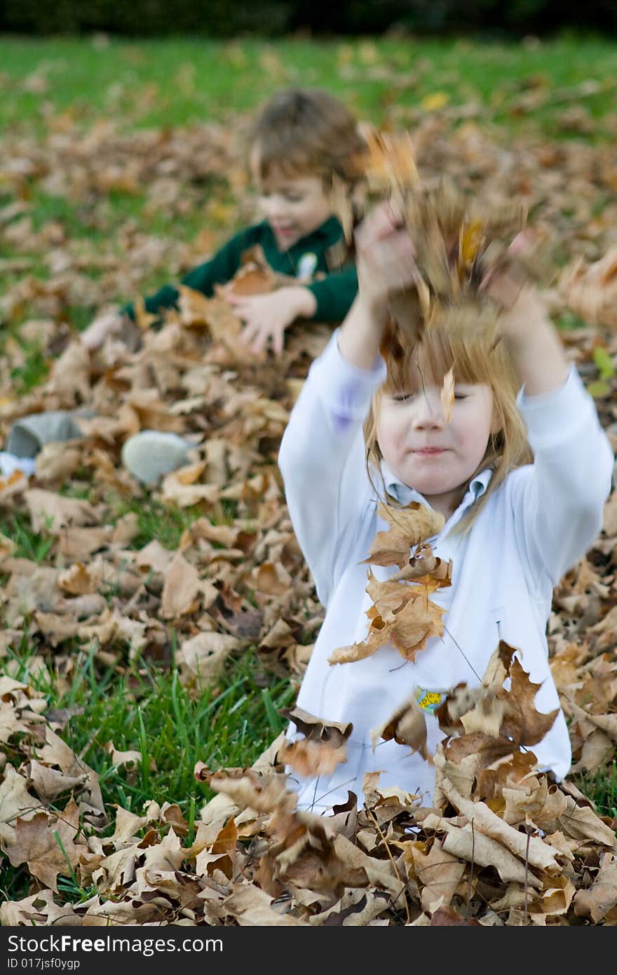 A set of boy girl twins playing in the autumn leaves