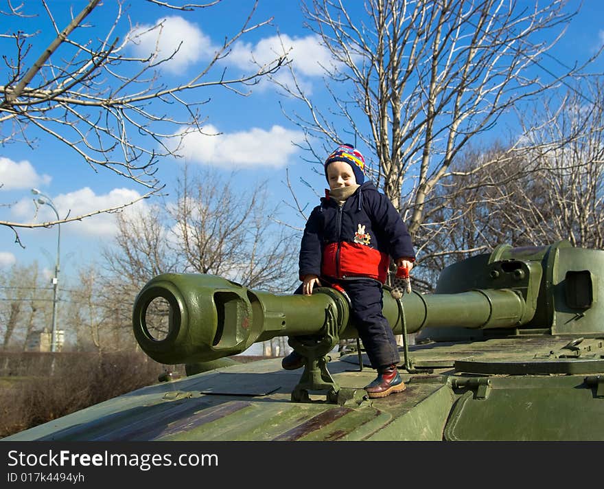 The smiling boy sits on a tank gun. The smiling boy sits on a tank gun